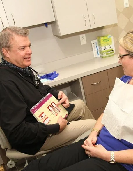 Dr. Larry Schmakel sitting down with a patient in a treatment room to talk through her options.