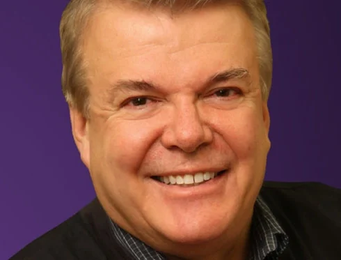 Dr. Larry Schmakel, smiling, photographed for his radio programme.