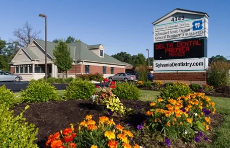 The Sylvania Smile Design sign at 4343 N. Holland-Sylvania Road, above a bed of summer flowers.